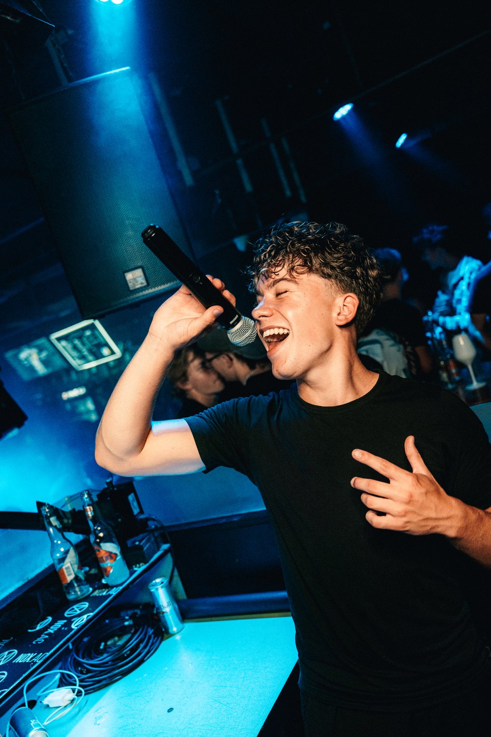 DJ Haemmer lacht und performt mit dem Mikrofon vor der Crowd